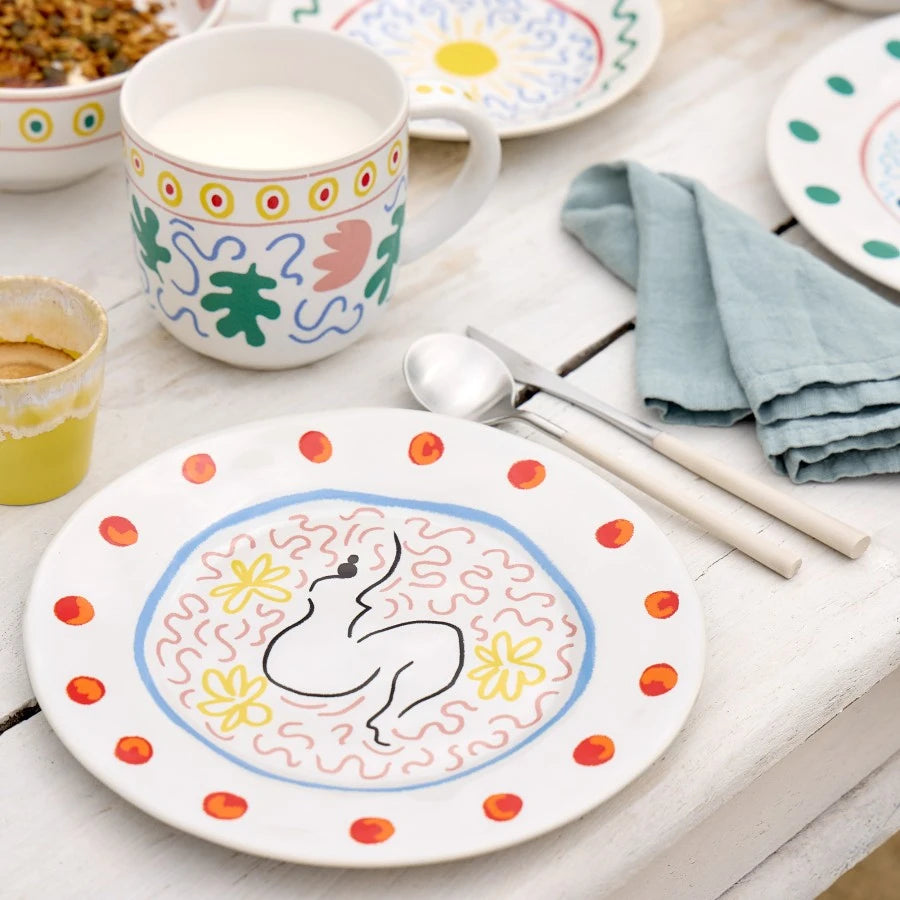 Mise en scène sur une table, cette assiette à dessert originale et épurée montre une silhouette de femme mise en valeur par des couleurs estivales.