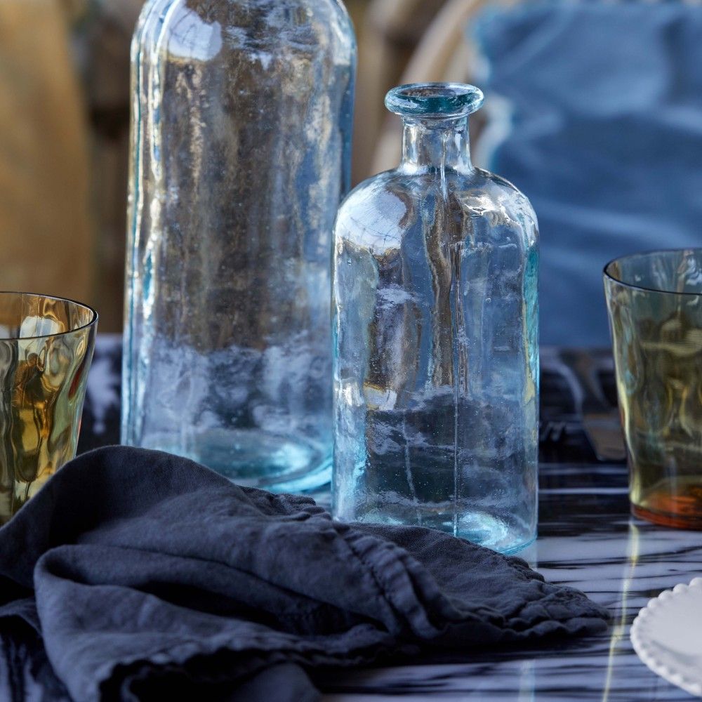 belle serviette de table bleu denim 100% lin posée au milieu de carafes à eau et verres costa nova. Maison gabin décoration