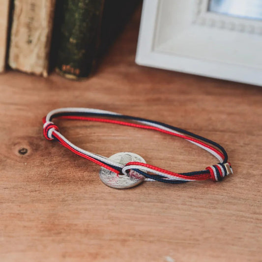 un bracelet avec un cordon ajustable tricolore et sa pièce trouée en étain le sou français