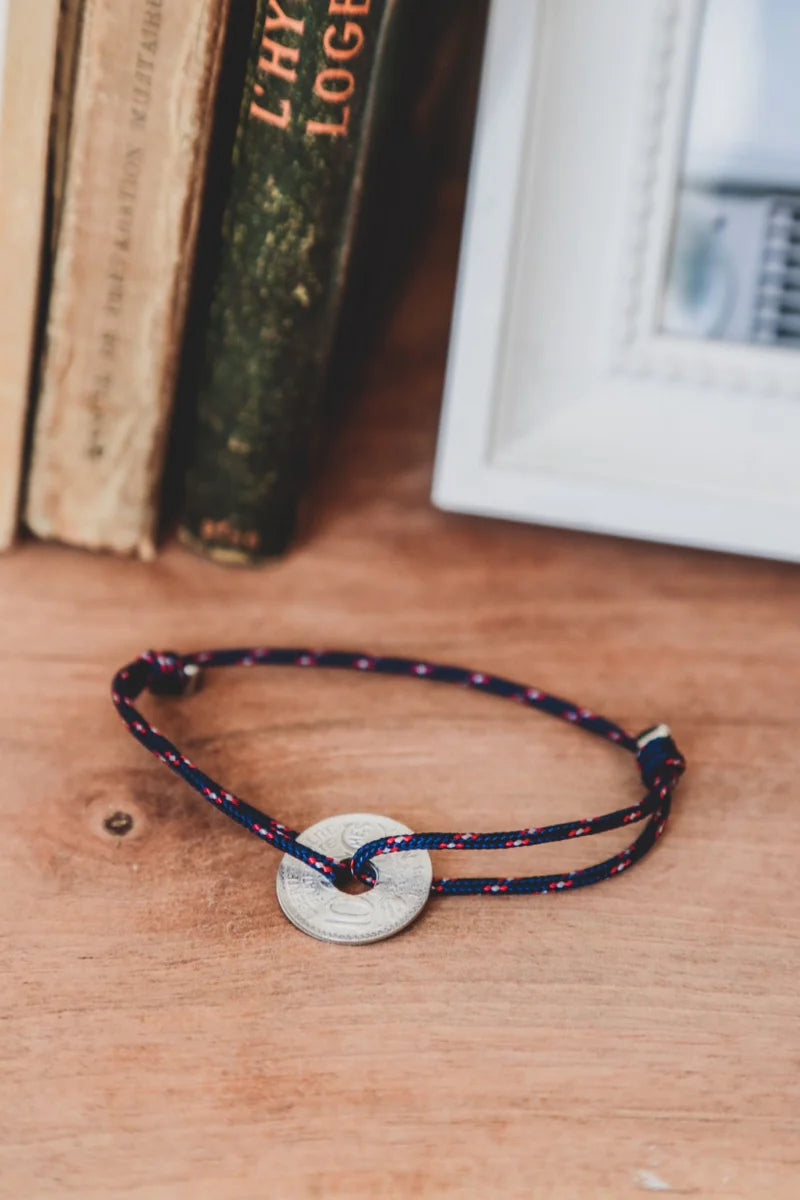 un bracelet marque française avec une pièce de monnaie en étain trouée pour un cordon ajustable bleu blanc rouge. Maison gabin décoration