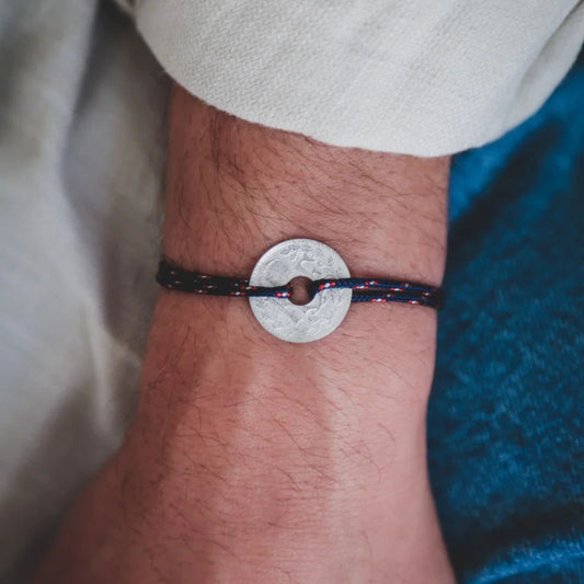 un bracelet avec la monnaie française le sou en étain et son cordon bleu marine moucheté  blanc et rouge