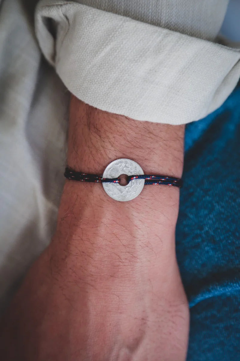 un bracelet avec la monnaie française le sou en étain et son cordon bleu marine moucheté  blanc et rouge. Maison gabin decoration