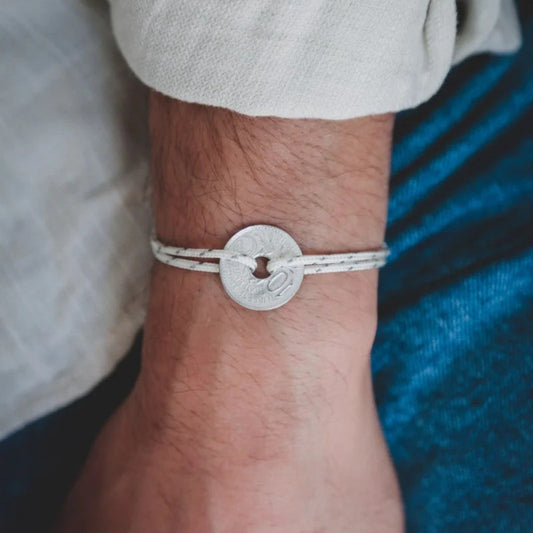 un bracelet blanc moucheté ajustable à tous les poignets et sa monnaie française le sou trouée