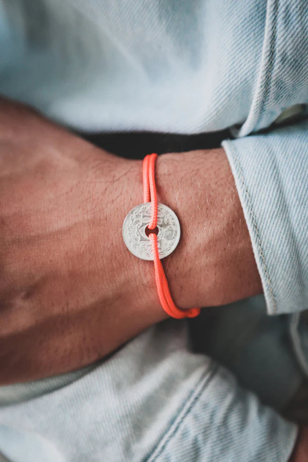 un bracelet avec un cordon orange ajustable et un sou, la monnaie française. Maison gabin décoration