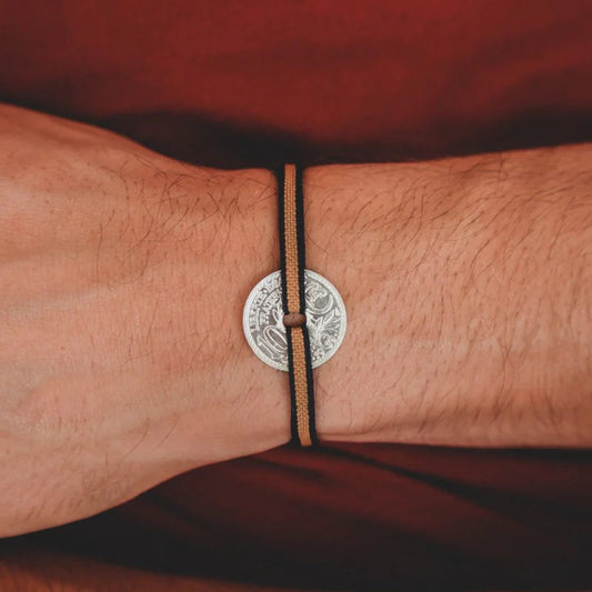 un bracelet unisexe avec une piece de monnaie le sou et son cordon élastique ajustable couleur ambre et liseret noir
