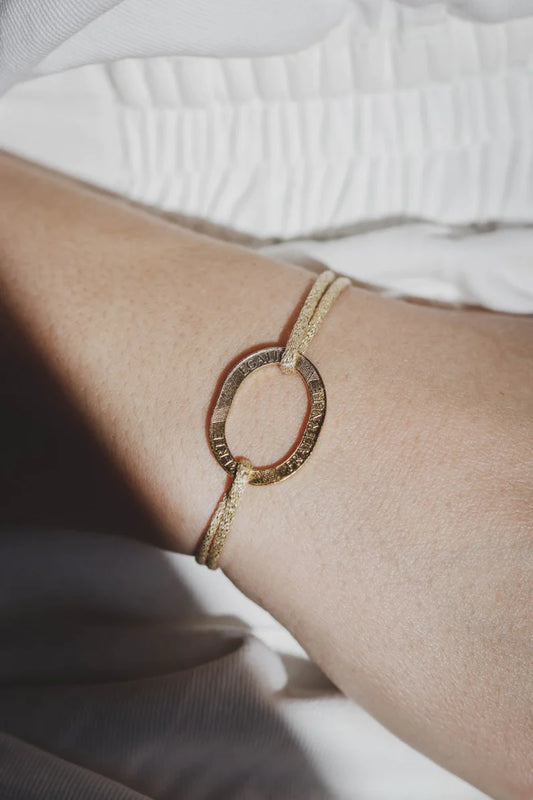 un bracelet pour femme avec une pièce de monnaie 10 francs évidée plaquée or et un cordon irisé doré réglable. Maison gabin décoration