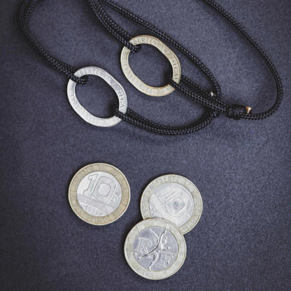 bracelet en cordon de coton noir avec une pièce de 10 francs trouée