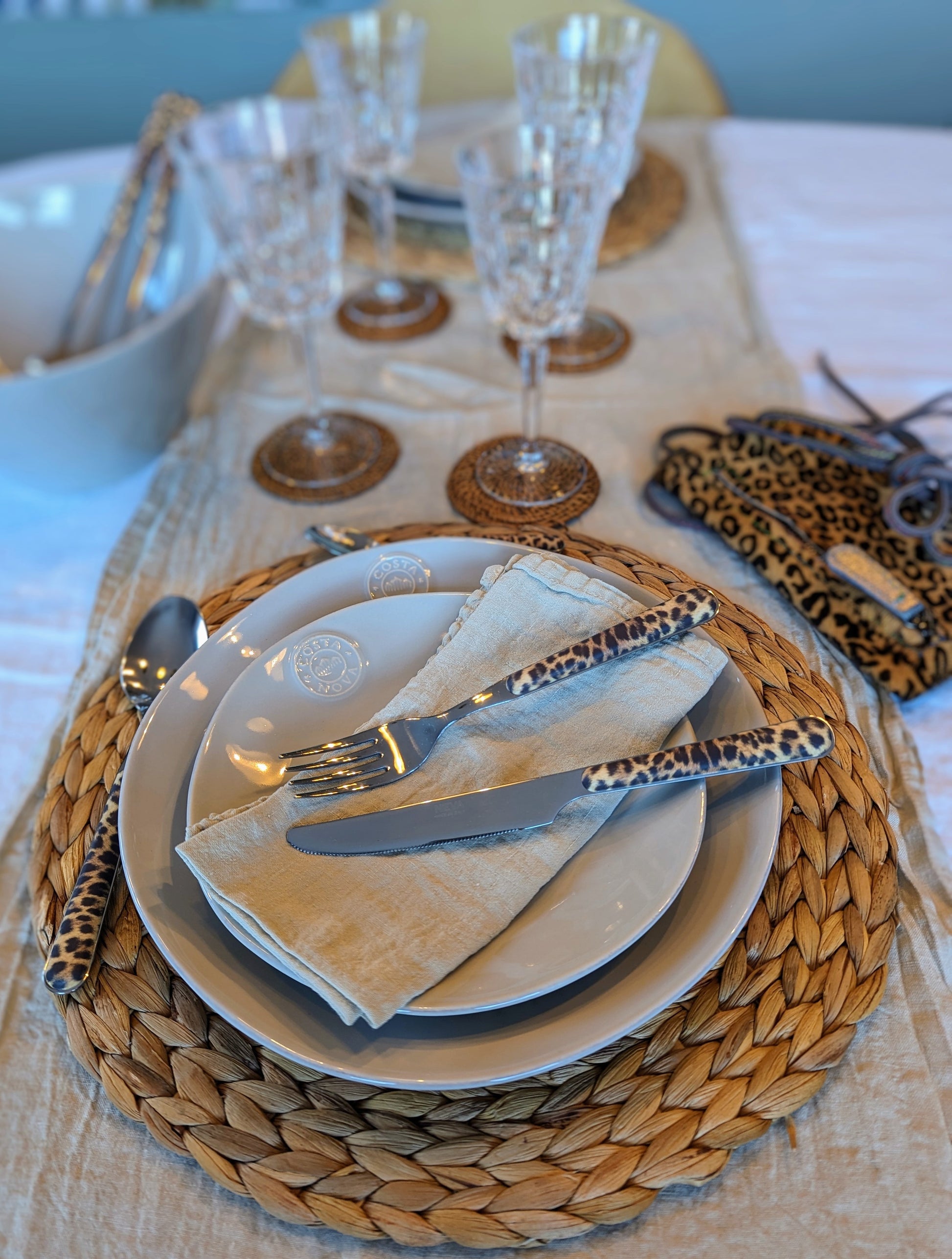 un chemin de table kaki clair accueillant une vaisselle beige en grès fin, une serviette en lin beige et des couverts leopard. Maison gabin décoration