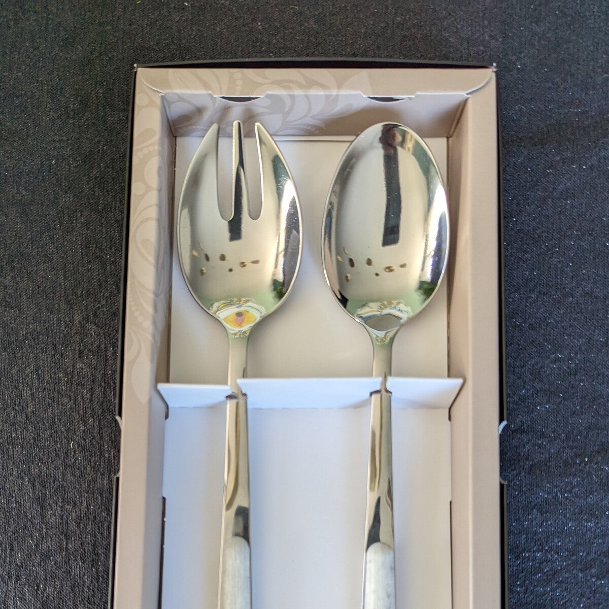 la fourchette et la cuillère en inox, présentent un manche en imitation bois blanchi. Ils sont vendus par 2 dans une boite